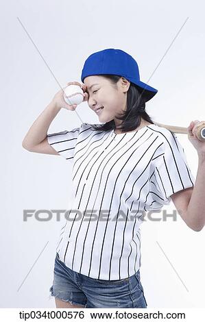 Stock Photograph - A female baseball player with a ball and bat. Fotosearch