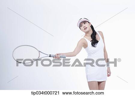 Stock Image - A female tennis player swing a racket. Fotosearch