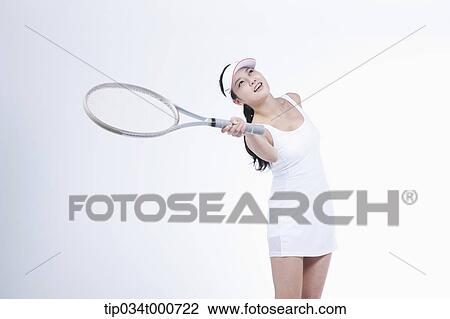Stock Image - A female tennis player swing a racket. Fotosearch