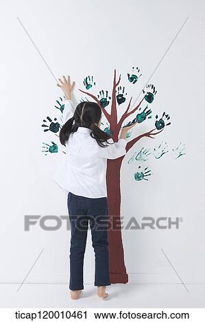 Stock Image - A girl painting the tree with hands. Fotosearch