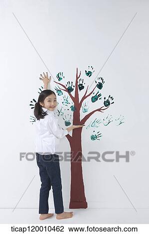 Stock Image - A girl painting the tree with hands. Fotosearch