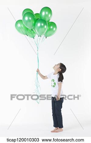 Stock Image - A girl wearing recycling shirt with green balloons. Fotosearch