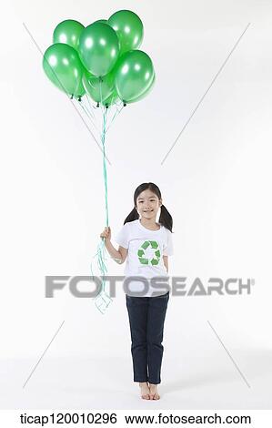 Stock Photograph - A girl wearing recycling shirt with green balloons. Fotosearch