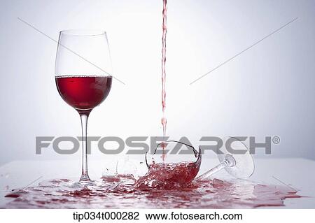 Stock Image - A glass of wine and dropping wine onto a broken glass. Fotosearch