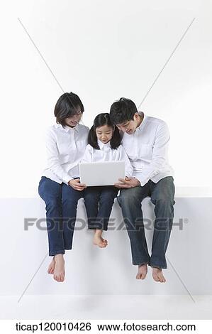 Stock Photograph - A happy family looking at the laptop . Fotosearch