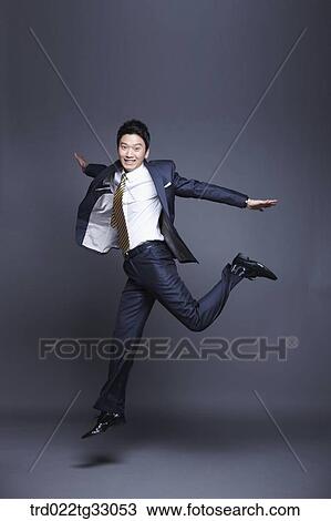 Stock Image - A jumping businessman with his arms open. Fotosearch