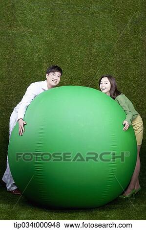 Stock Photo - A man and woman resting on a green ball. Fotosearch