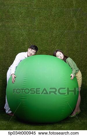 Stock Photography - A man and woman resting on a green ball. Fotosearch