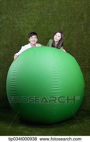 Stock Photo - A man and woman touching on a green ball. Fotosearch