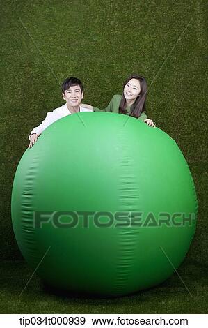Stock Photo - A man and woman touching on a green ball. Fotosearch