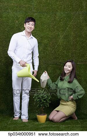 Stock Image - A man and woman watering the tree. Fotosearch