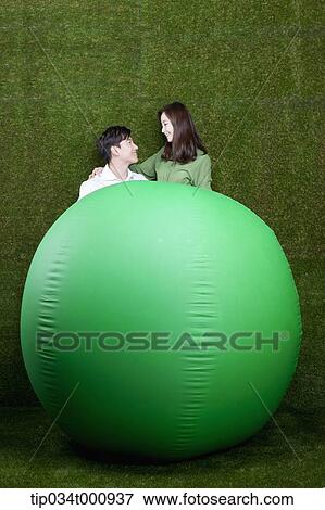 Stock Photo - A man and woman with a green ball. Fotosearch