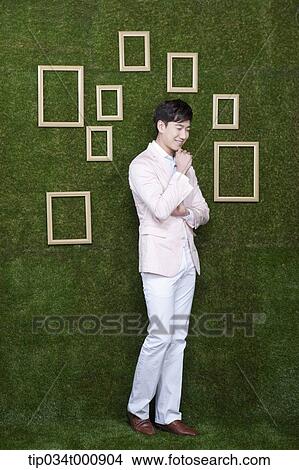 Picture - A man and wooden frames on the green wall. Fotosearch