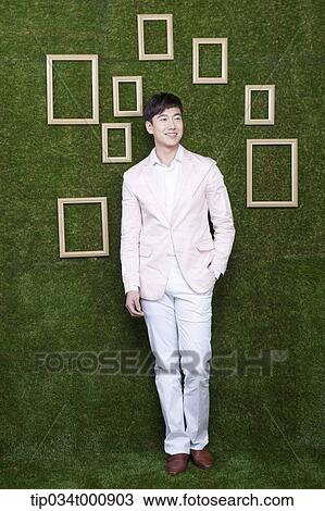 Stock Image - A man and wooden frames on the green wall. Fotosearch