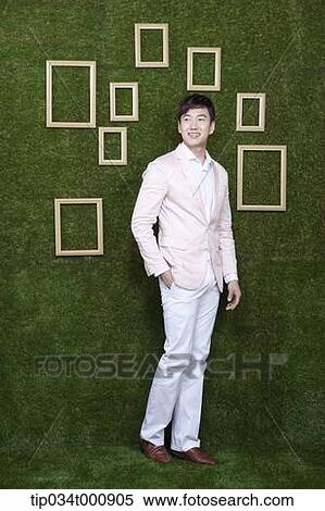 Stock Photography - A man and wooden frames on the green wall. Fotosearch