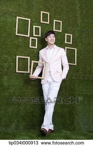A man holding a frame from the green wall View Large Photo Image Stock Image - A man holding a frame from the green wall. Fotosearch
