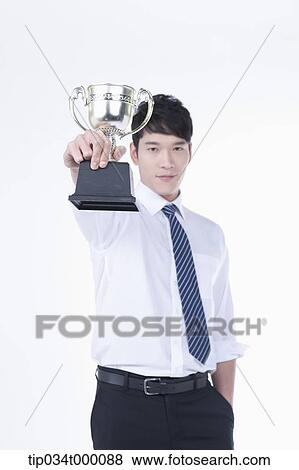 Stock Photo - A man holding a trophy. Fotosearch