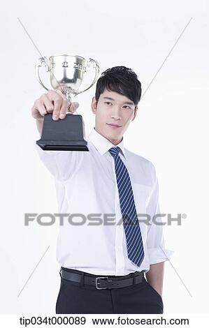 Stock Photo - A man holding a trophy. Fotosearch