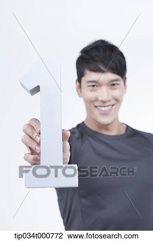 Stock Image - A man holding the number one. Fotosearch