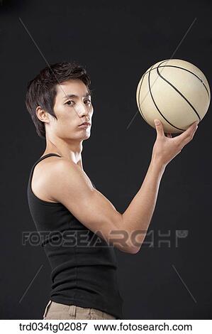 Stock Photo - A man holding up a basketball. Fotosearch