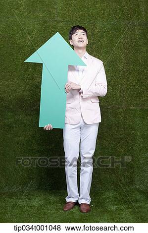Stock Photo - A man looking above with a green arrow. Fotosearch