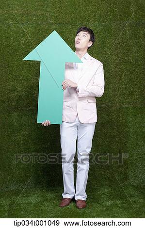 Stock Photo - A man looking above with a green arrow. Fotosearch