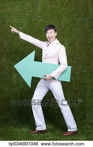 Stock Photograph - A man pointing at left side with a green arrow. Fotosearch