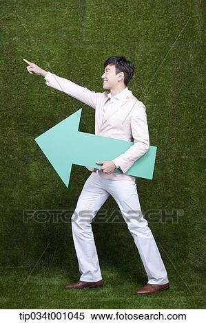 Stock Photography - A man pointing at left side with a green arrow. Fotosearch
