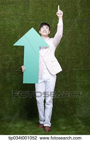 Stock Image - A man pointing at the sky with a green arrow. Fotosearch