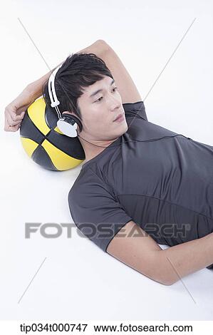 Stock Photo - A man resting on the basketball with the headset on . Fotosearch