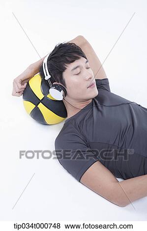 A man resting on the basketball with the headset on View Large Photo Image Stock Photo - A man resting on the basketball with the headset on . Fotosearch