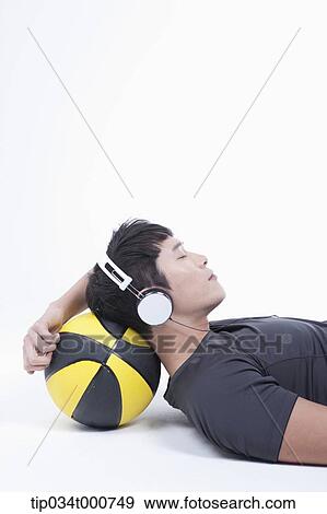 A man resting on the basketball with the headset on View Large Photo Image Stock Photo - A man resting on the basketball with the headset on . Fotosearch