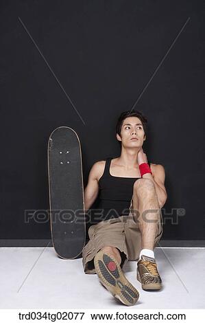 A man sitting with a skateboard View Large Photo Image Stock Photo - A man sitting with a skateboard. Fotosearch