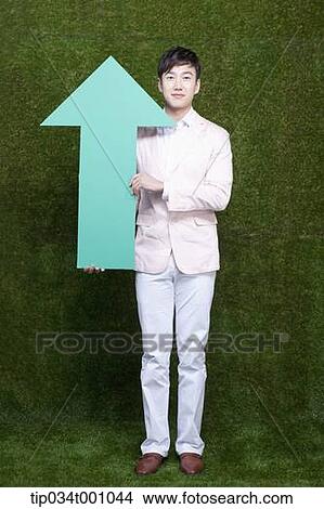 Picture - A man standing with a green arrow. Fotosearch