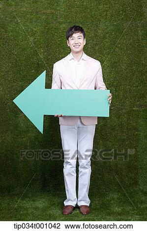 Stock Image - A man standing with a green arrow. Fotosearch