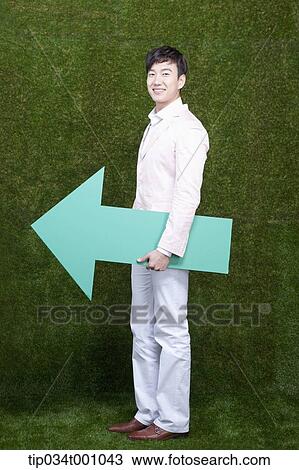 Stock Image - A man standing with a green arrow. Fotosearch