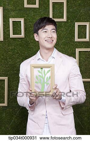 Stock Image - A man with a frame of green tree. Fotosearch