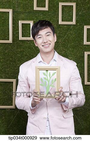 Stock Photo - A man with a frame of green tree. Fotosearch