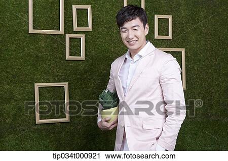 Stock Image - A man with a green cactus pot. Fotosearch
