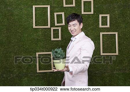 Stock Image - A man with a green cactus pot. Fotosearch