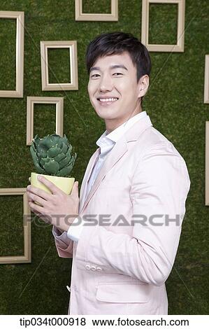 Stock Photo - A man with a green cactus pot. Fotosearch