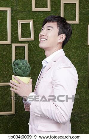 Stock Photo - A man with a green cactus pot. Fotosearch