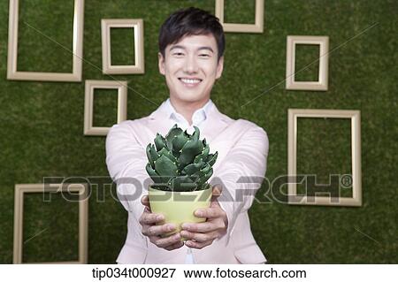 Stock Photo - A man with a green cactus pot. Fotosearch