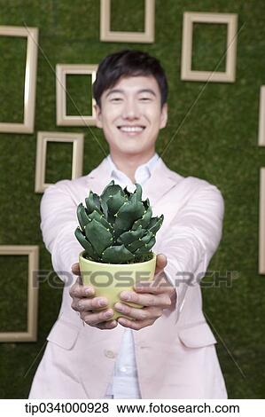 Stock Photo - A man with a green cactus pot. Fotosearch
