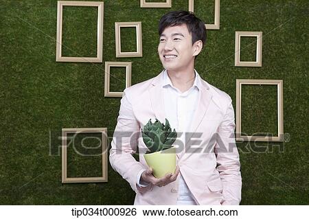 Stock Photograph - A man with a green cactus pot. Fotosearch