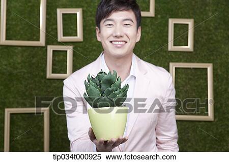 Stock Photography - A man with a green cactus pot. Fotosearch