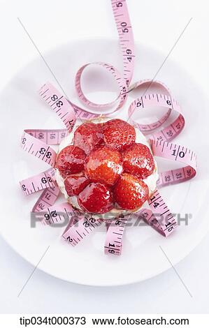 Stock Image - A measuring tape and cake on the dish . Fotosearch