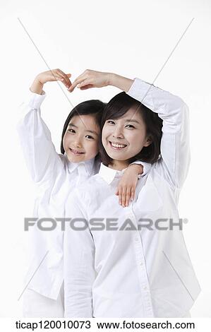 Stock Image - A mother and daughter making heart over the head. Fotosearch
