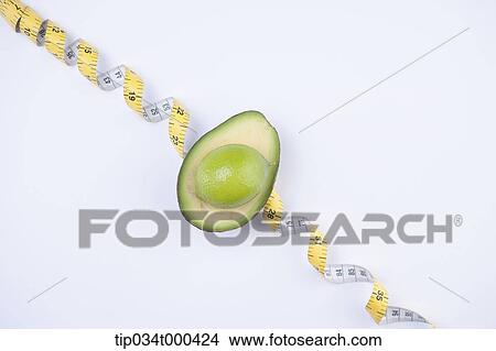 Picture - A piece of avocado and a measuring tape. Fotosearch