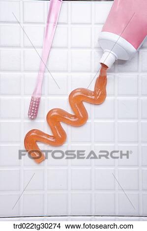 Picture - A pink tooth brush and orange tooth paste from tube. Fotosearch
